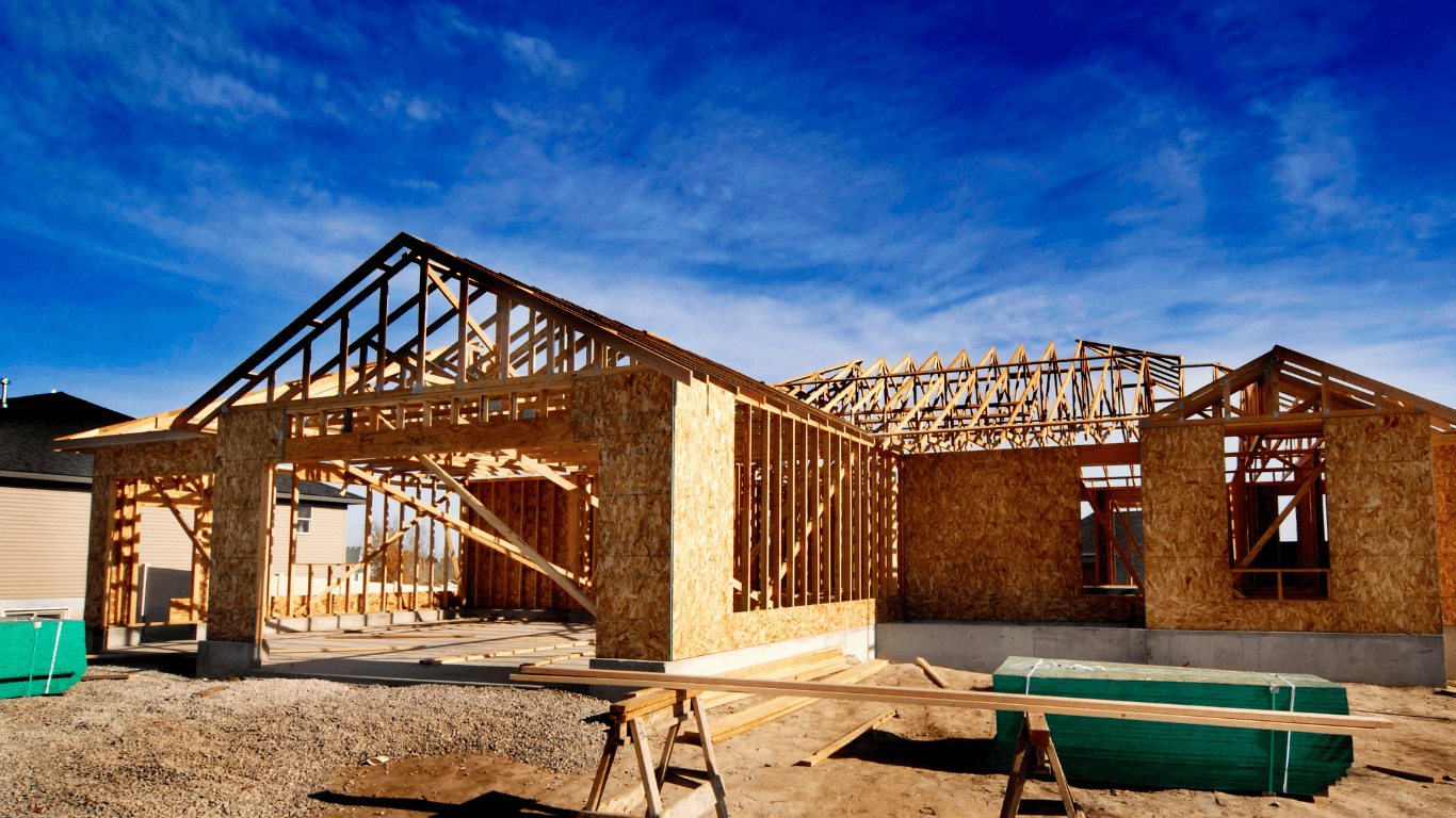 Timber-framed residential home under construction with exposed trusses and wall framing
